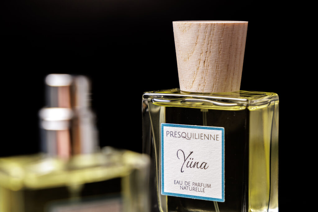 Gros plan sur le flacon du parfum artisanal Yüna de Presquilienne avec son bouchon en bois naturel.